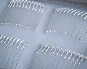May include: Four silver hair combs with a fine-toothed design. The combs are arranged in a grid pattern on a white surface.