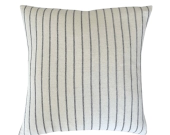 May include: A white pillow with gray vertical stripes. The pillow is made of a soft, textured fabric.