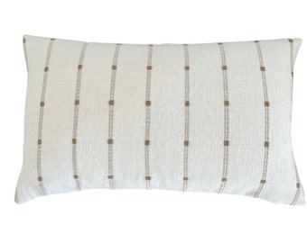 May include: A white rectangular pillow with brown stripes and small brown squares.