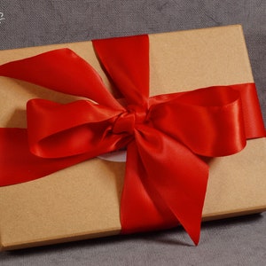 May include: A brown cardboard gift box tied with a bright red satin ribbon bow.