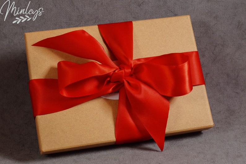May include: A brown cardboard gift box tied with a bright red satin ribbon bow.