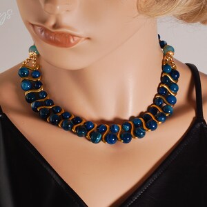 May include: A gold and blue necklace with a wavy design. The necklace is made of blue agate beads and gold wire.