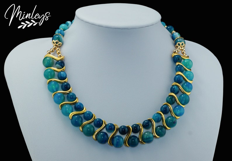 May include: A double-strand necklace with blue agate beads and gold accents. The beads are graduated in size and have a swirling pattern.