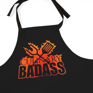 May include: Black apron with an orange and yellow flame design and the text "Culinary Badass".