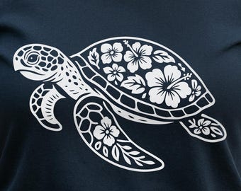 May include: Navy blue t-shirt featuring a white sea turtle design with floral accents. The turtle's shell is adorned with hibiscus flowers. The shirt also includes the text "This Feels So Good" and "Designed for Dark Surfaces".
