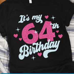Puede incluir: Camiseta negra con un diseño rosa brillante que dice "It's my 64th Birthday".