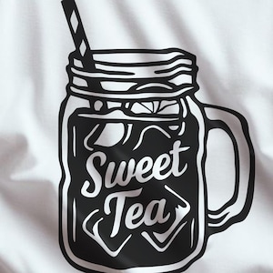 Op de afbeelding: Wit T-shirt met een zwart-witte afbeelding van een weckpot gevuld met ijs en een rietje, met de woorden "Sweet Tea" in een gestileerd lettertype. Het shirt heeft ook de tekst "SVG and PNG file format".