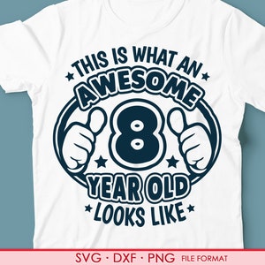 Puede incluir: Camiseta blanca con un gráfico azul que dice "This is what an awesome 8 year old looks like" con un pulgar hacia arriba a cada lado del número 8.