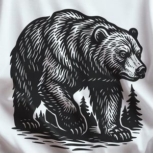 Puede incluir: Camiseta blanca con una ilustración en blanco y negro de un oso. El oso se representa sentado, con un bosque de fondo. La camiseta también incluye el texto "DESCARGA DIGITAL" y "This Feels So Good" con "SVG y PNG FORMATO DE ARCHIVO".