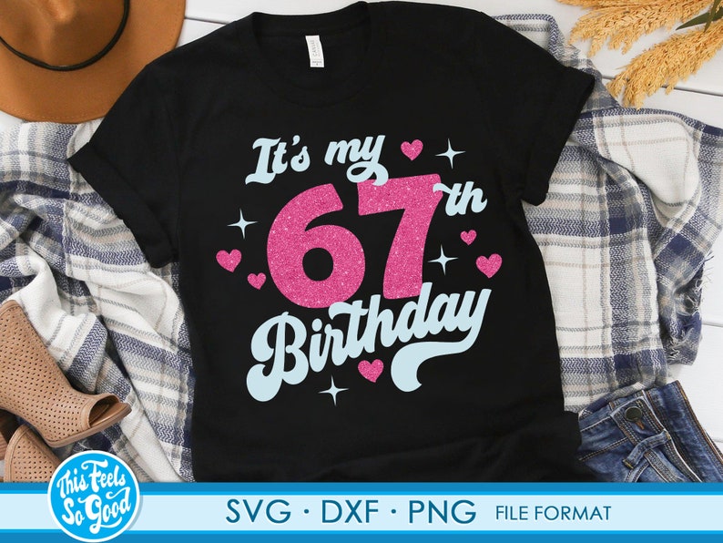 May include: Black t-shirt with the text "It's my 67th Birthday" in pink and blue glitter lettering. The shirt is decorated with small pink hearts and stars.
