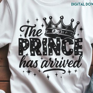 Puede incluir: Camiseta blanca con un gráfico negro que dice "The Prince has arrived" con una ilustración de corona encima de la palabra "Prince". La palabra "Prince" está llena de estrellas. La camiseta también tiene el texto "SVG and PNG file format".