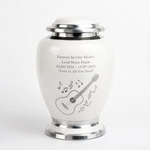 May include: A white ceramic mug with a black handle and the text "But First, Coffee" in a black, handwritten-style font. The mug is on a white surface.