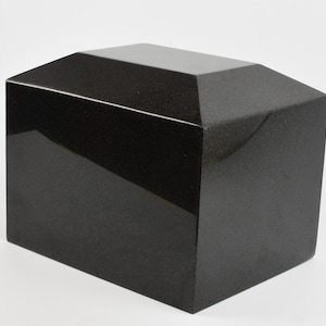 May include: A black granite cremation urn with a rectangular shape and a slightly angled top.