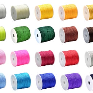 May include: A selection of colourful cord spools in shades like white, yellow, green, pink, red, blue, and brown. Each spool is tightly wound and mounted on a white plastic core. The cords appear to be made of a smooth, durable material.