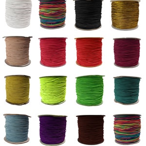 May include: Assortment of 16 spools of elastic cord in various colours, including white, black, gold, red, green, blue, purple, and rainbow. The spools are arranged in four rows of four.