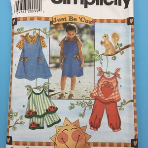 Puede incluir: Patrón de costura Simplicity número 7571 para las tallas 5, 6, 7 y 8. El patrón se titula "Just Be 'Cuz" y presenta tres atuendos diferentes para un niño. El primer atuendo es un vestido de mezclilla azul con una blusa de estampado floral amarillo y blanco. El segundo atuendo es una blusa a rayas verde y blanca con detalles de mariquita roja y pantalones a juego. El tercer atuendo es una blusa de cuadros rojos y blancos con un corazón rojo y pantalones rojos a juego.