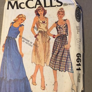May include: Vintage McCall's sewing pattern envelope with illustrations of three dresses: a blue maxi dress, a beige dress with a bow, and a plaid dress. The envelope displays the number 6611 and the text "Carefree Patterns from McCall's".