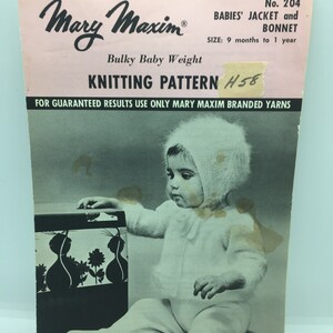 May include: A black and white photo of a baby wearing a white knitted jacket and bonnet. The baby is sitting on the floor and holding a black and white toy. The photo is from a vintage knitting pattern for a baby's jacket and bonnet. The pattern number is 204 and the pattern is for babies 9 months to 1 year old. The pattern is for bulky baby weight yarn.