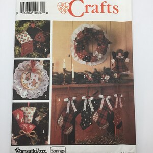 May include: A Simplicity Crafts sewing pattern for making Christmas decorations. The pattern includes instructions for making a wreath, stockings, ornaments, and a gingerbread man. The pattern is for one size and is printed on white paper with red and black text.
