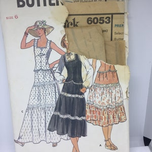 Puede incluir: Un patrón de costura vintage para un vestido con tres estilos diferentes. El patrón es para la talla 6 y se llama "Quick! Butterick 6053".