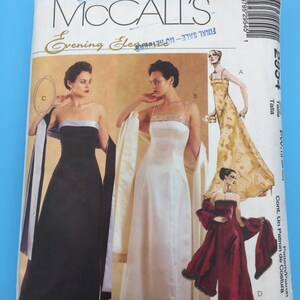 May include: McCall's Evening Elegance sewing pattern for a dress. The pattern includes three different styles: a black strapless gown with a white sash, a white strapless gown with a beaded neckline, and a red strapless gown with a black trim.
