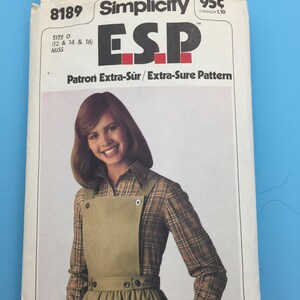May include: Simplicity sewing pattern number 8189, ESP Extra-Sûr/Extra-Sure Pattern, size O (12, 14, and 16) for misses. The pattern features a woman wearing a brown and white checked shirt and a brown overall dress with a gathered skirt.