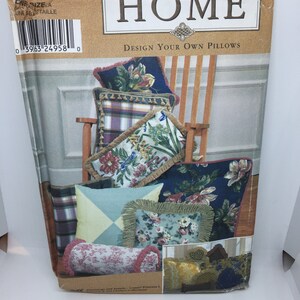 Könnte beinhalten: Ein Simplicity Home Nähmuster zum Entwerfen eigener Kissen. Der Musterumschlag zeigt eine Vielzahl von Kissen mit verschiedenen Stoffen und Besätzen, darunter florale, karierte und geometrische Muster.