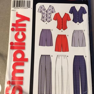 May include: Simplicity sewing pattern with designs for tops and trousers. The pattern includes short-sleeved blouses, shorts, and wide-leg trousers. The pattern size is A 8-18. The text "IT'S SO easy" is visible.