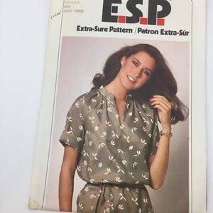 May include: Simplicity sewing pattern number 10612814 for a dress. The pattern is called "ESP Extra-Sure Pattern/Patron Extra-Sûr" and costs $1.10. The pattern shows a woman wearing a green and white floral print dress with a V-neck and short sleeves.
