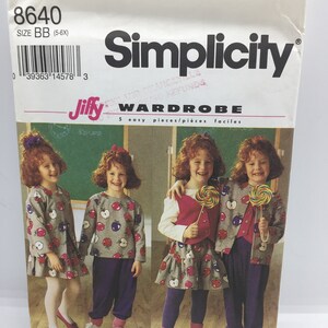 May include: Simplicity sewing pattern number 8640 for a Jiffy Wardrobe. The pattern is for sizes 5-6X and includes five easy pieces. The pattern shows four girls wearing different outfits from the pattern. The girls are wearing a grey and red apple print top, a purple vest, a purple skirt, and purple pants.