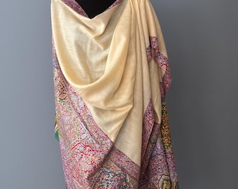May include: A cream-colored shawl with a colorful paisley pattern border. The shawl is draped over a black mannequin.