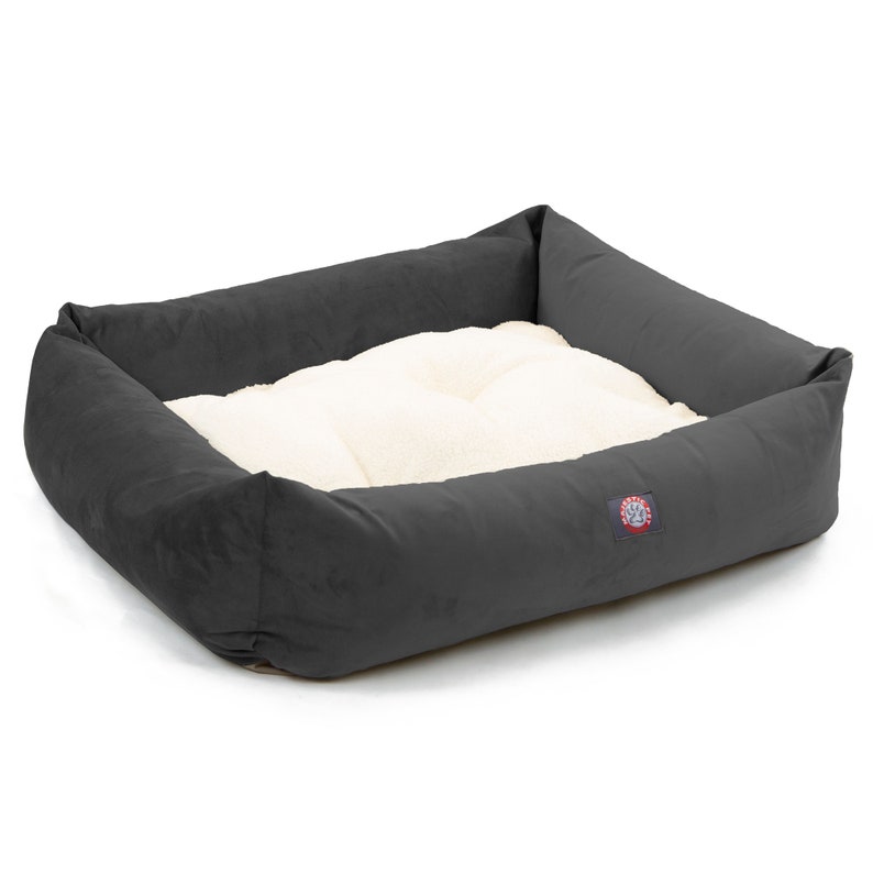 Puede incluir: Una cama para perros gris con un forro blanco de felpa. La cama tiene un borde elevado y un logotipo en el lateral.