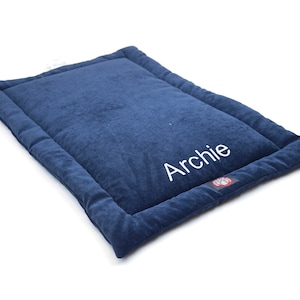 May include: A blue dog bed with a white embroidered name "Archie".