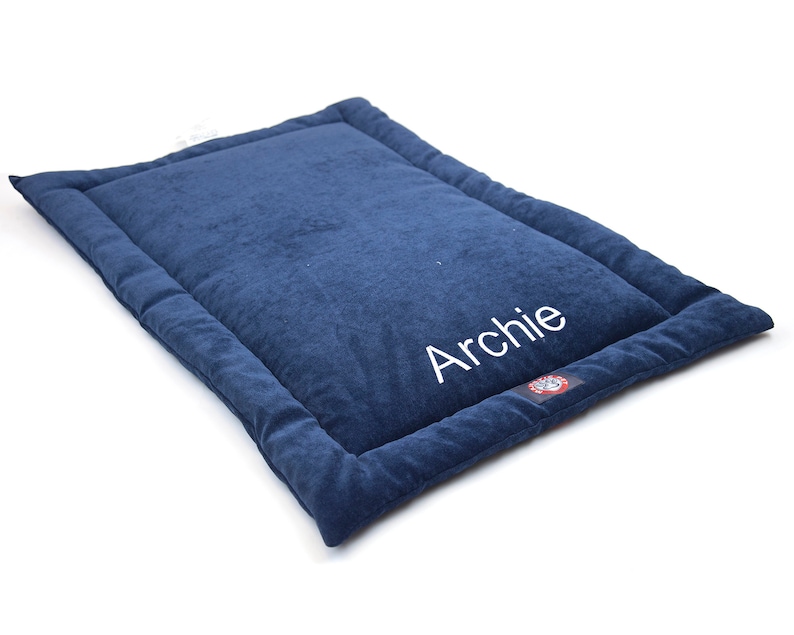May include: A blue dog bed with a white embroidered name "Archie".