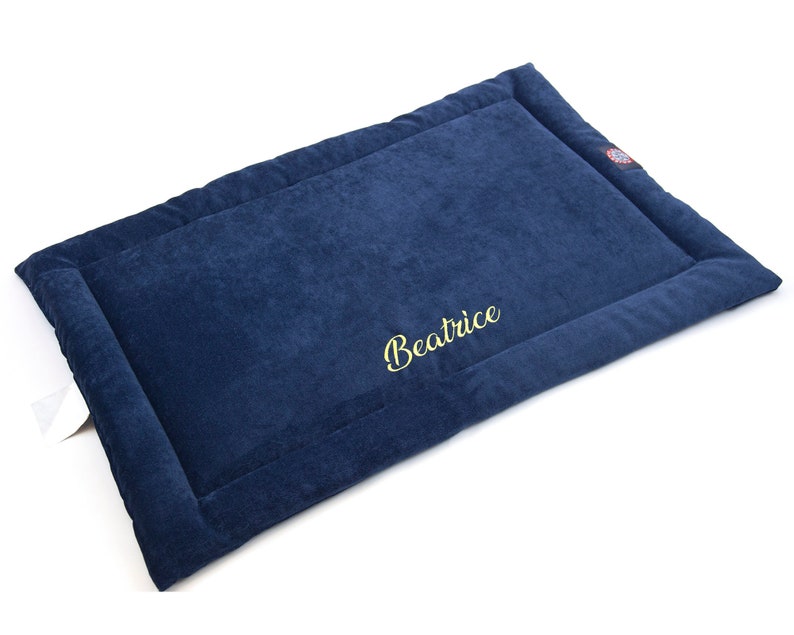 May include: A navy blue pet bed with a gold embroidered name "Beatrice".