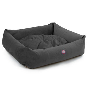 Puede incluir: Una cama para perros gris con un borde elevado y un interior suave y mullido. La cama tiene un peque&ntilde;o logotipo en el lateral.