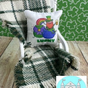 May include: A white rocking chair with a green and white plaid throw blanket and a white pillow with a cartoon leprechaun holding a pot of gold and a beer. The pillow says "Lucky" on it.