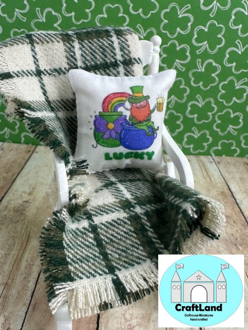 May include: A white rocking chair with a green and white plaid throw blanket and a white pillow with a cartoon leprechaun holding a pot of gold and a beer. The pillow says "Lucky" on it.