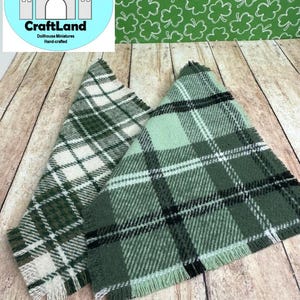 May include: Two green and white plaid fabric squares with frayed edges. The fabric has a woven texture and is a light green, dark green, white, and black plaid pattern.