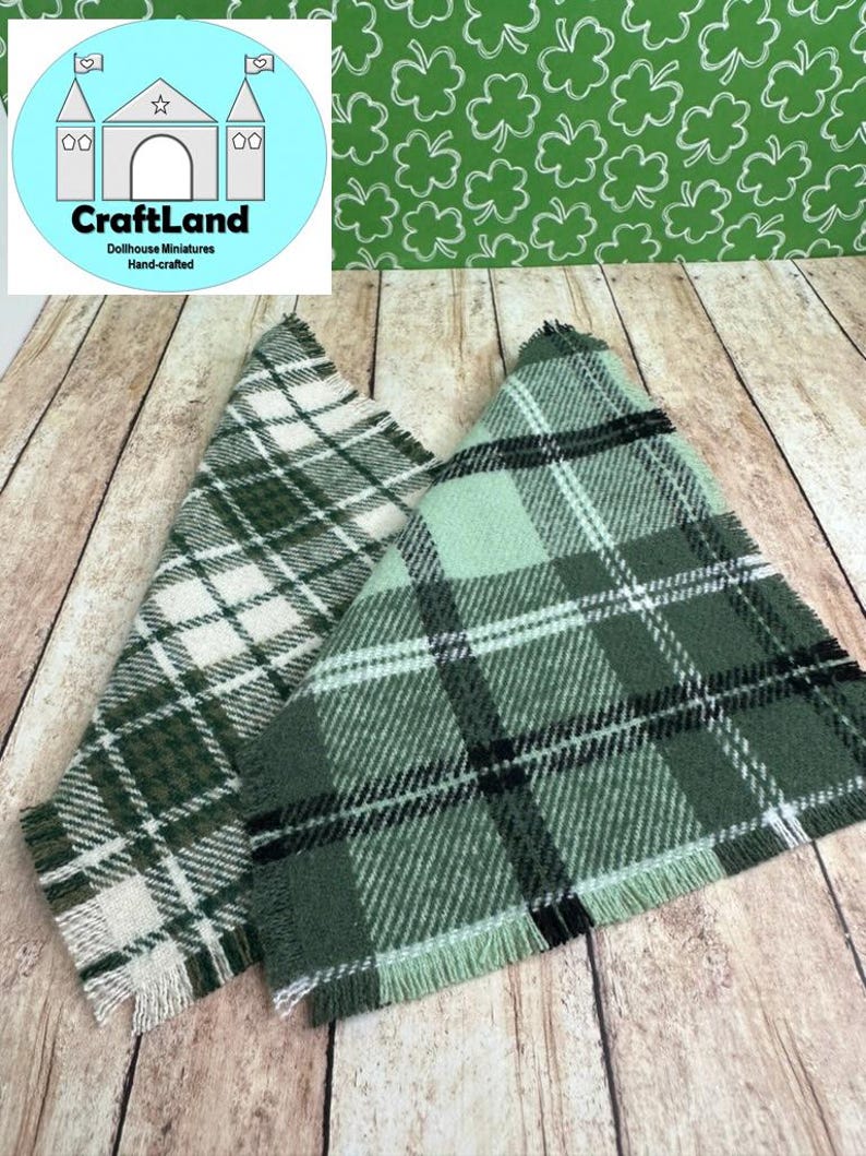 May include: Two green and white plaid fabric squares with frayed edges. The fabric has a woven texture and is a light green, dark green, white, and black plaid pattern.