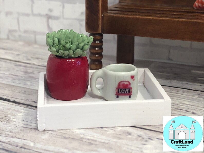 May include: A white tray with a red potted succulent and a white mug with a red car and the word "LOVE" on it.