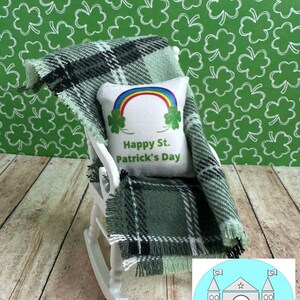 May include: A white rocking chair with a green and black plaid blanket and a white pillow with a rainbow and the text "Happy St. Patrick's Day".