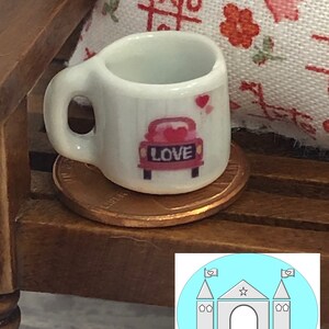 May include: White ceramic miniature mug with a red car and the word "LOVE" on it. The mug is sitting on a penny.
