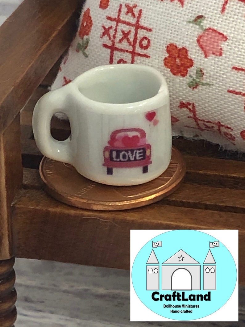May include: White ceramic miniature mug with a red car and the word "LOVE" on it. The mug is sitting on a penny.