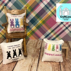 May include: Three miniature pillows with Easter bunny designs. The first pillow is white with black bunnies and the text "CARROT COMPANY Cake Juice Cookies Locally owned Est. Perry". The second pillow is white with colorful bunnies and the text "HOP ON". The third pillow is white with colorful bunnies and the text "Happy Easter".