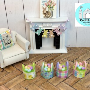 May include: Four miniature baskets filled with pastel colored Easter eggs. The baskets are decorated with different patterns, including plaid, floral, and bunny designs. A miniature fireplace with a bunny garland hangs above the fireplace.