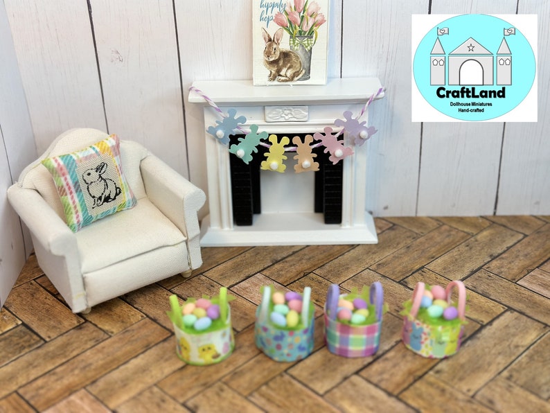 May include: Four miniature baskets filled with pastel colored Easter eggs. The baskets are decorated with different patterns, including plaid, floral, and bunny designs. A miniature fireplace with a bunny garland hangs above the fireplace.