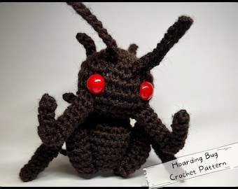 May include: A crocheted brown bug with red eyes. The bug has long legs and antennae. The text "Hoarding Bug Crochet Pattern" is on a white label.