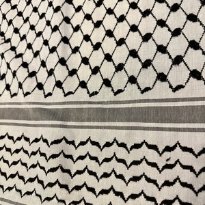 May include: A white and black patterned fabric with a geometric design. The fabric has a traditional Middle Eastern style.