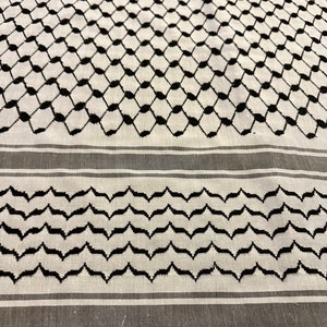 May include: A white and black patterned fabric with a geometric design. The fabric has a black and white striped border.